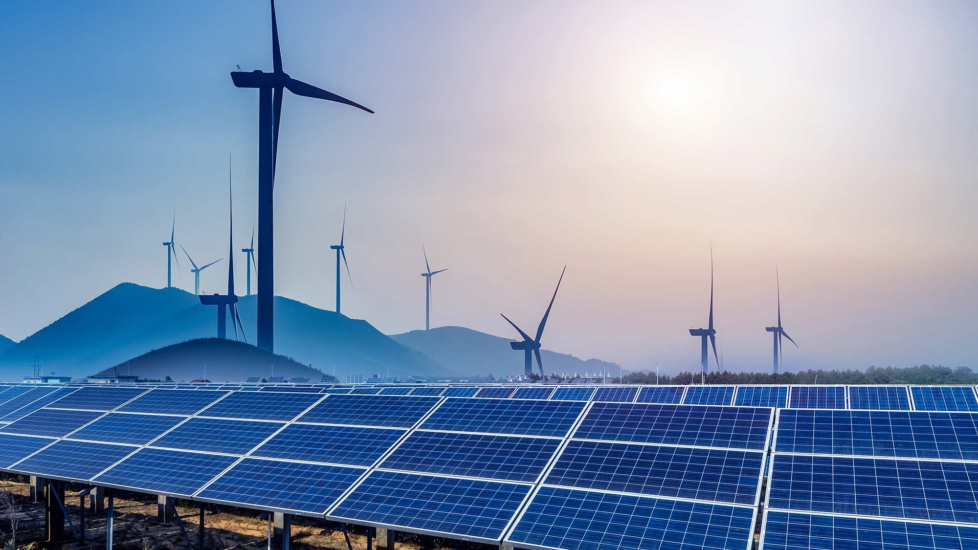 Solar panels with wind farm in background