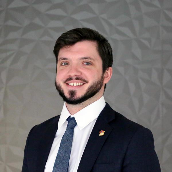 A man with dark hair and a beard smiling towards the camera.