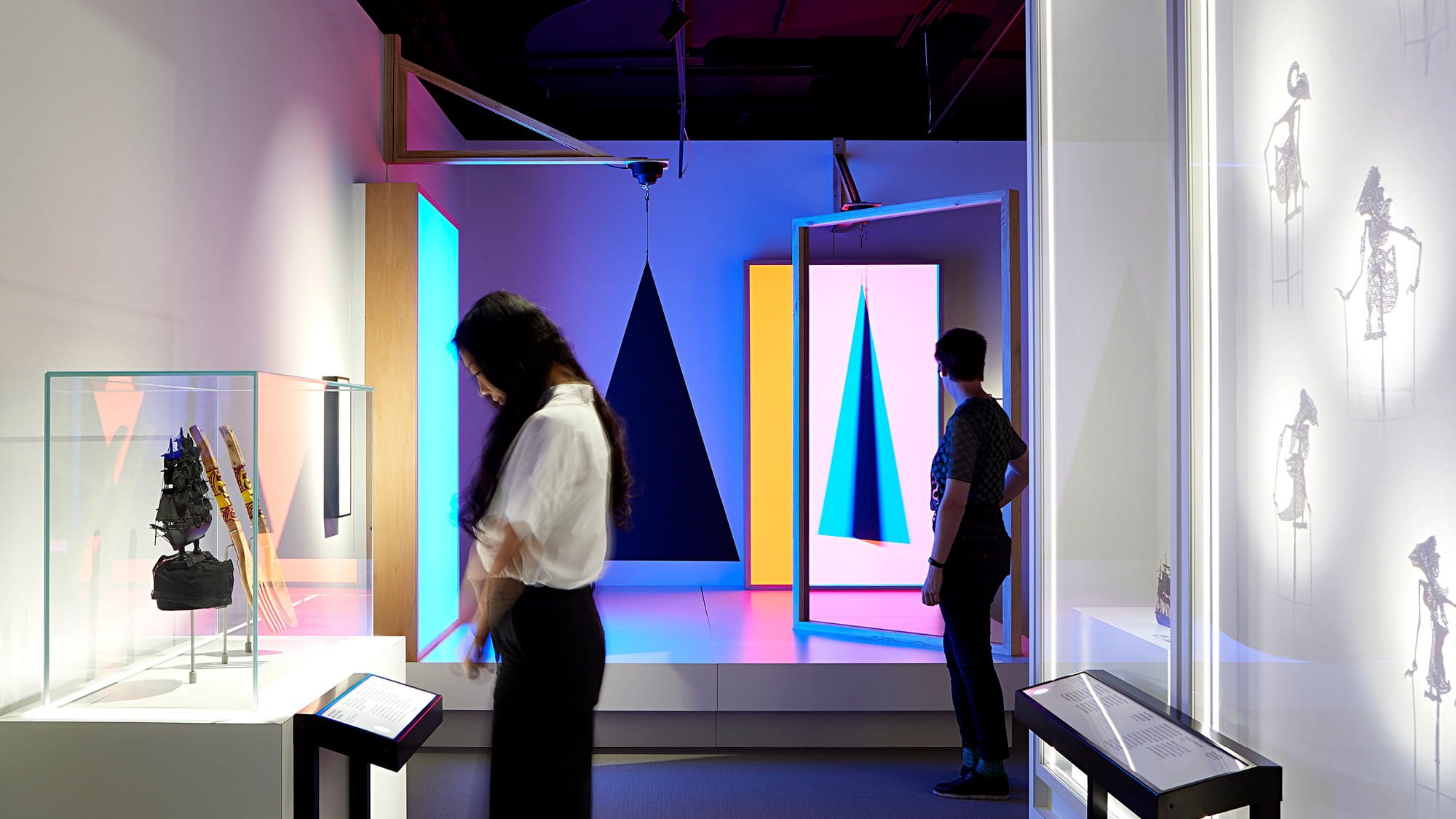 Visitors reading and looking at objects and film inside an exhibition