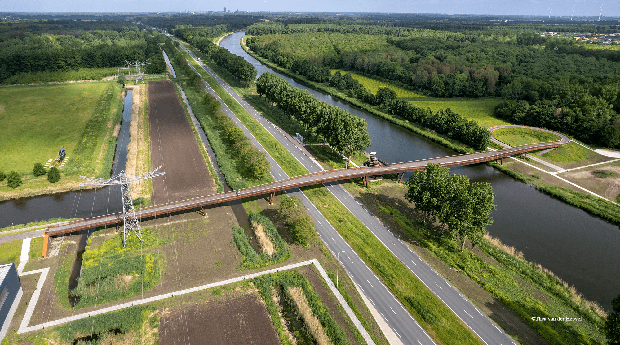 A rusty bridge crossing a water canal and a busy road