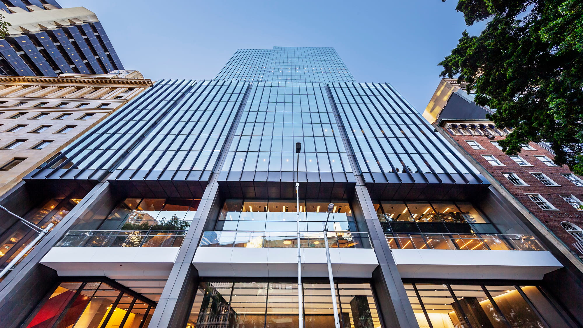 View from street, looking up at an office tower with glass facade at day time