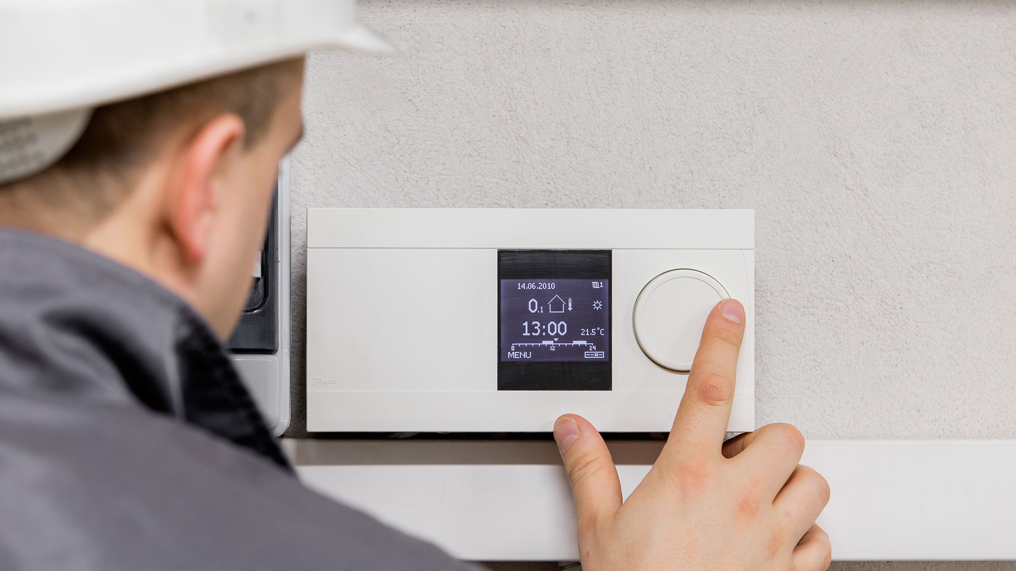 Engineer changes the heating on a thermostat