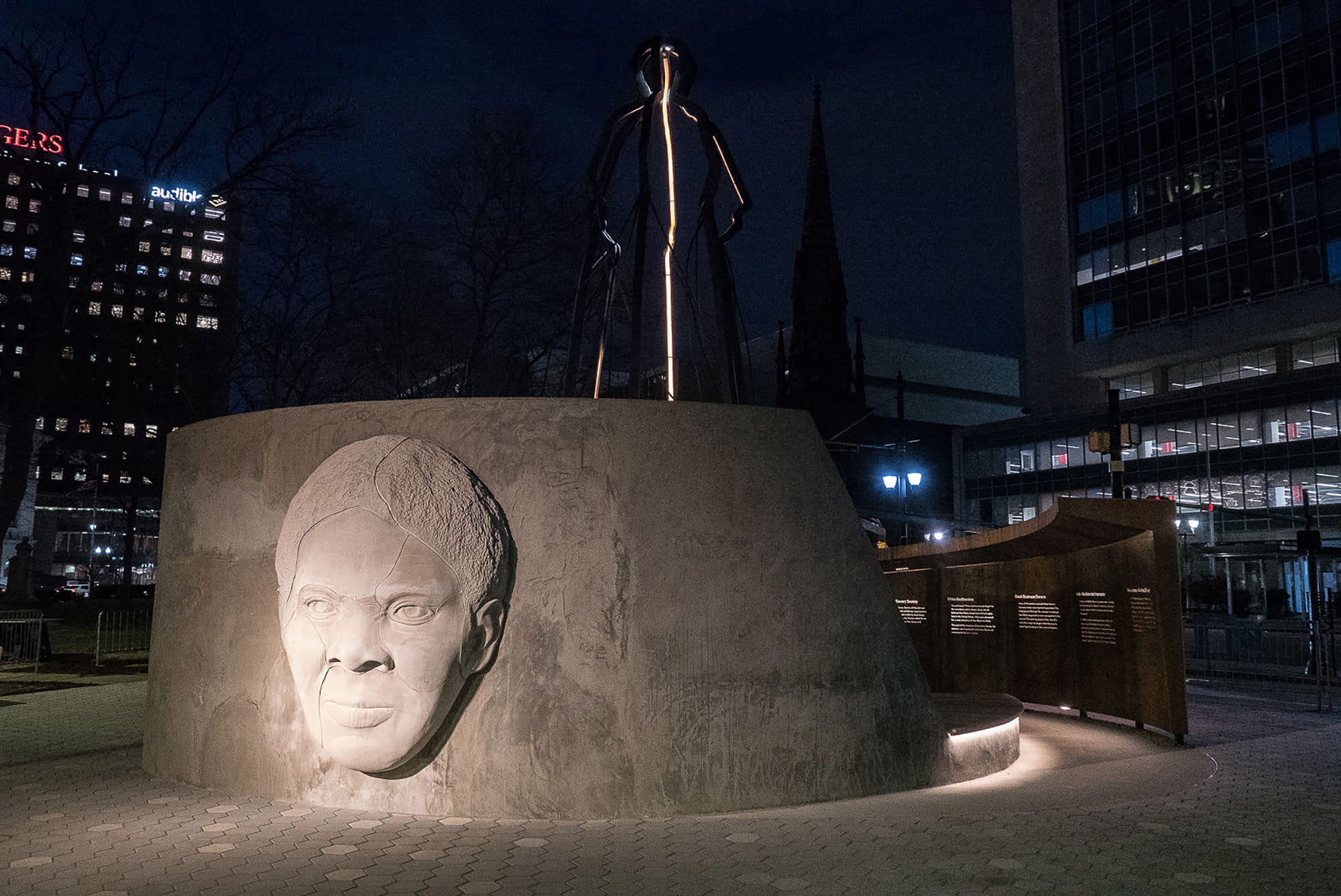 A nighttime image of a monument with a woman's face carved in stone