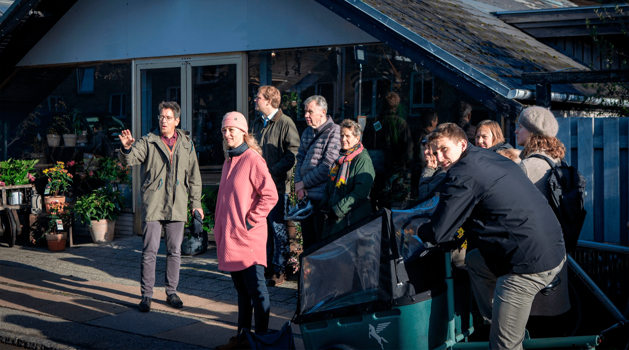 A grouo of people in front of a house with glass windows.