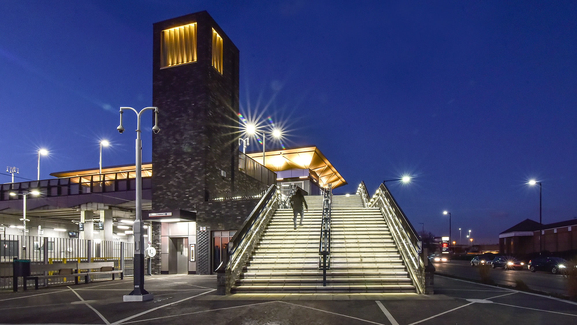 Meridian Water station at night showing illuminated roof and tower. 