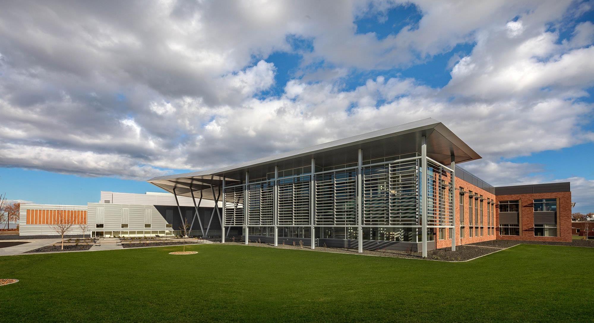 Front entrance of the PNNL laboratory during the daytime. There is a large metal awning and criss-crossing beams. 