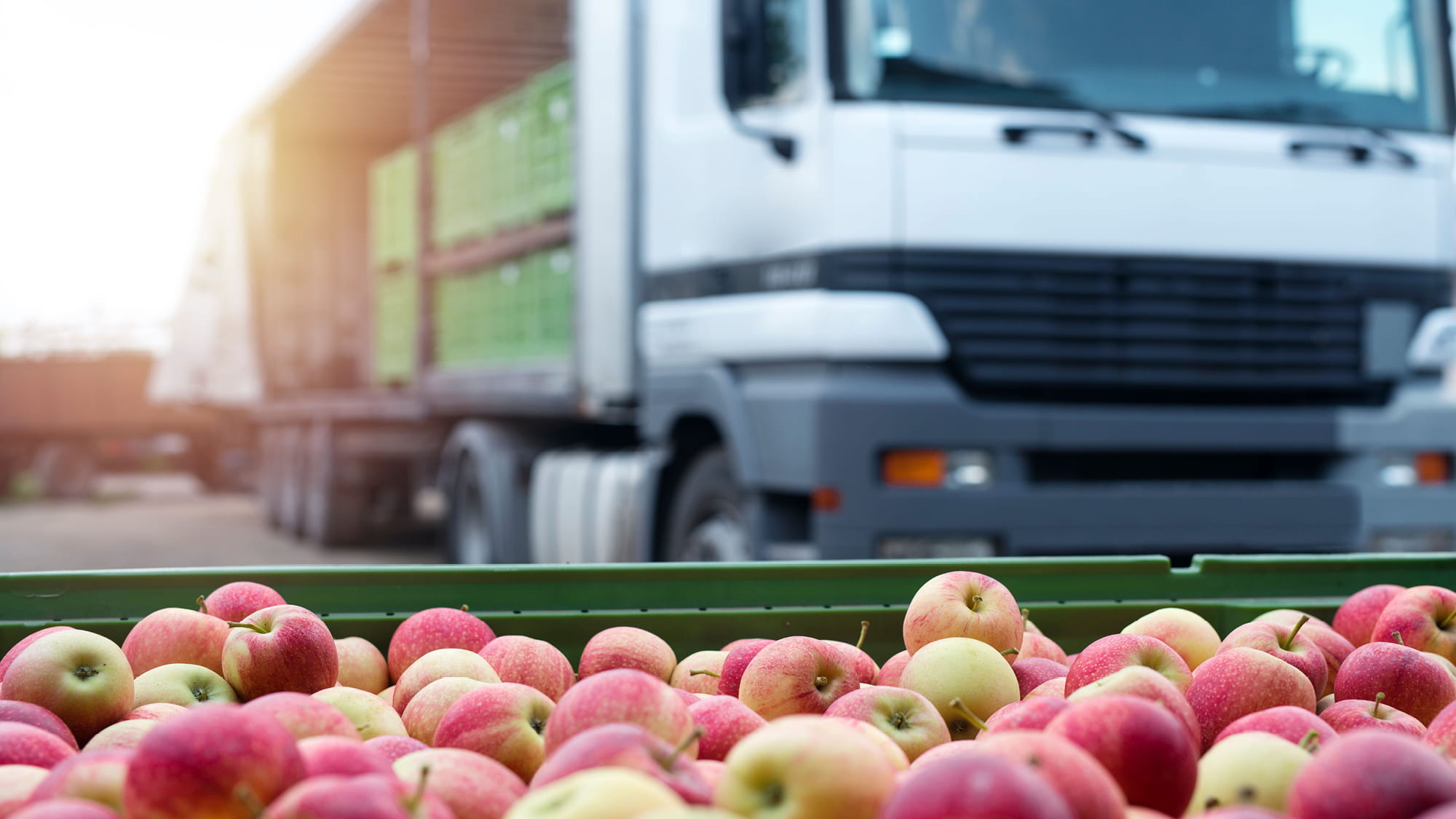 A cart of apples in front of a truck in the day time