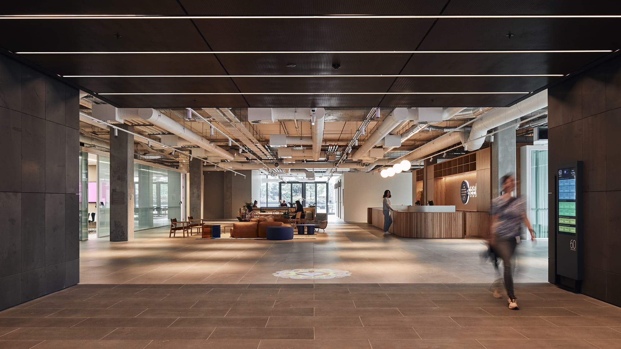 Inside a modern office reception area with brown timber floors, furnishings and plants