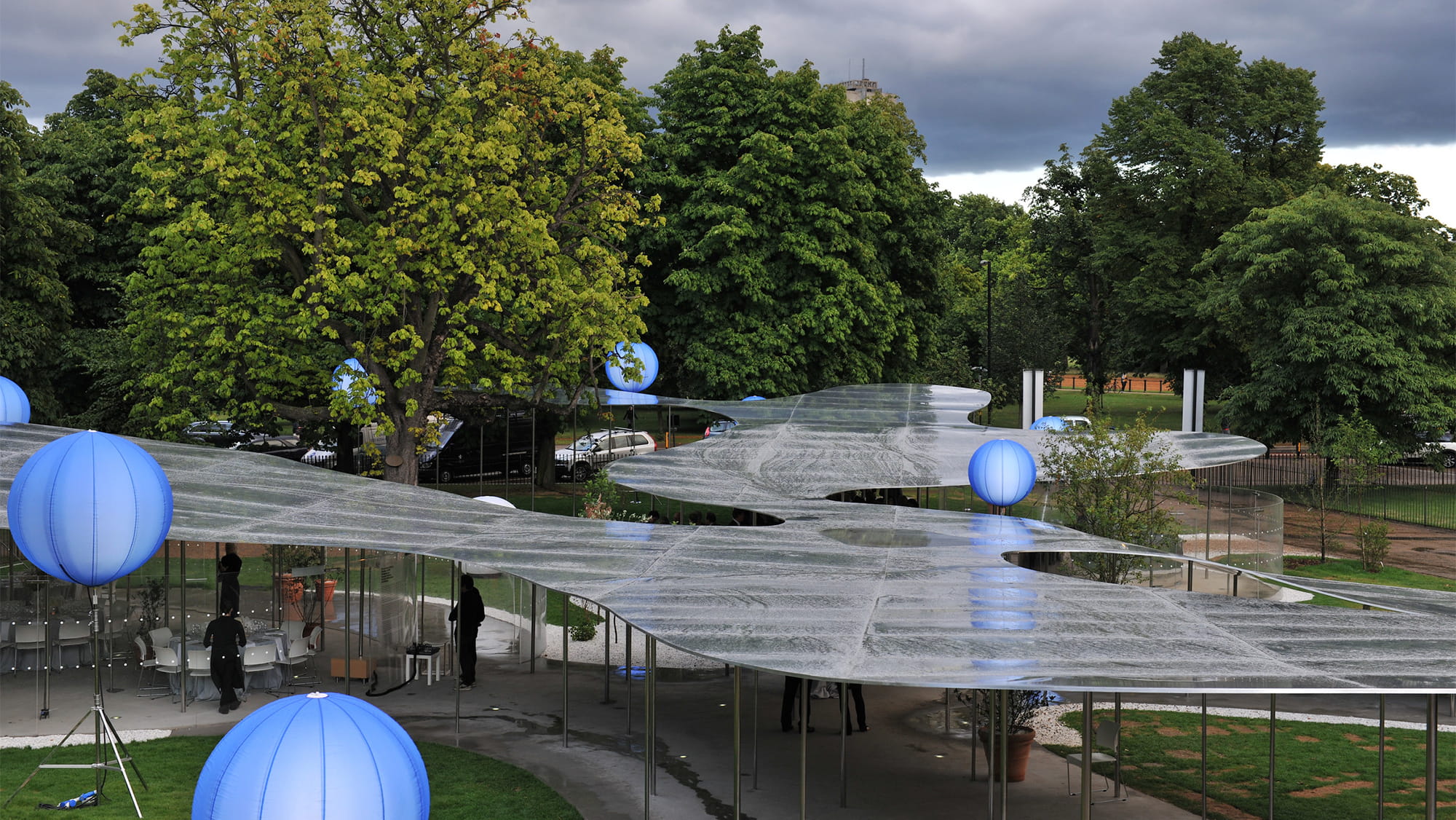 The 2009 Serpentine Pavilion resembles a reflective cloud or a floating pool of water, sitting atop a series of delicate columns. The aluminium roof structure varies in height, wrapping itself around trees in the park. Photo: Daniel Imade