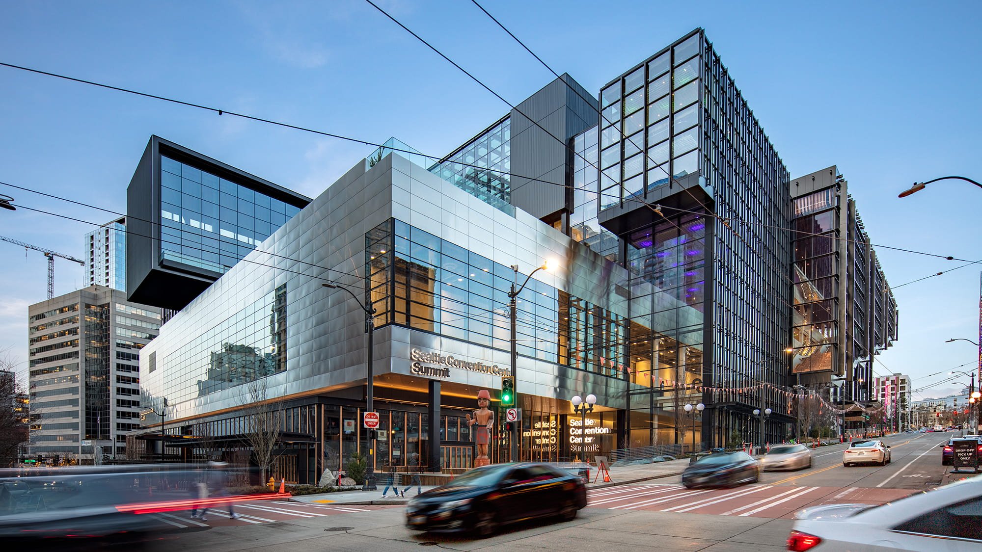 Daytime view of the convention center, the sky is blue and cars are driving by outside.