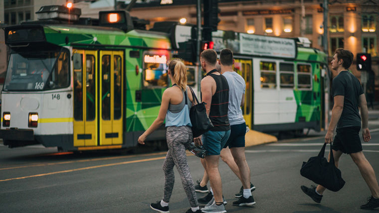People walking on a street with a tram in the background