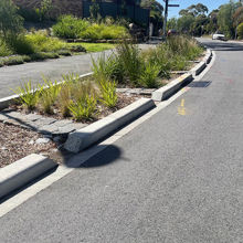 Extended curb alongside road with garden bed with pavers, pebbles and plants 